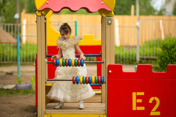 Little lovely girl in an elegant dress on the playground