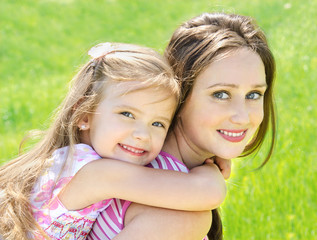 portrait of smiling beautiful young woman and her little daughte