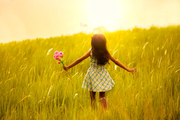 Little girl running on meadow with sunset