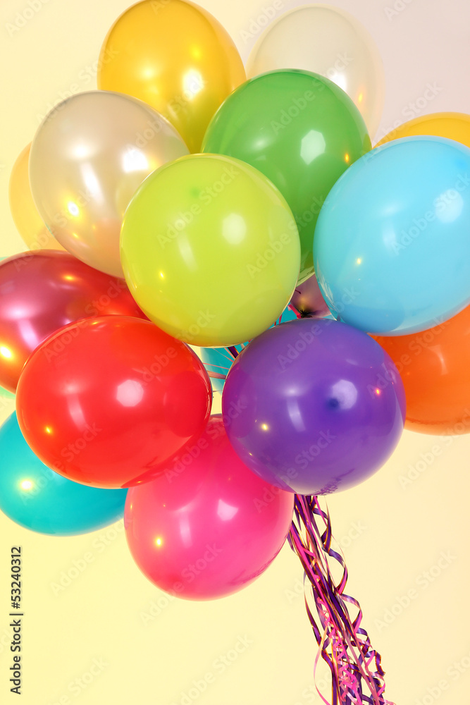 Many bright balloons on yellow background