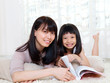 © szeyuen - Asian woman and daughter lying on the floor and reading