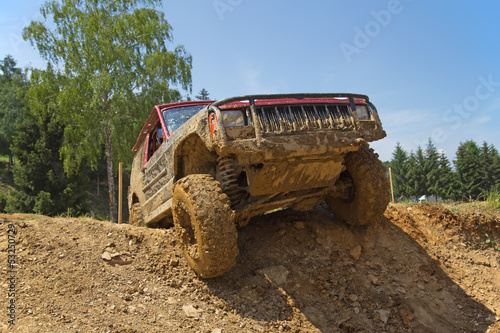 Naklejka na szybę Red SUV overcomes steep muddy slope.