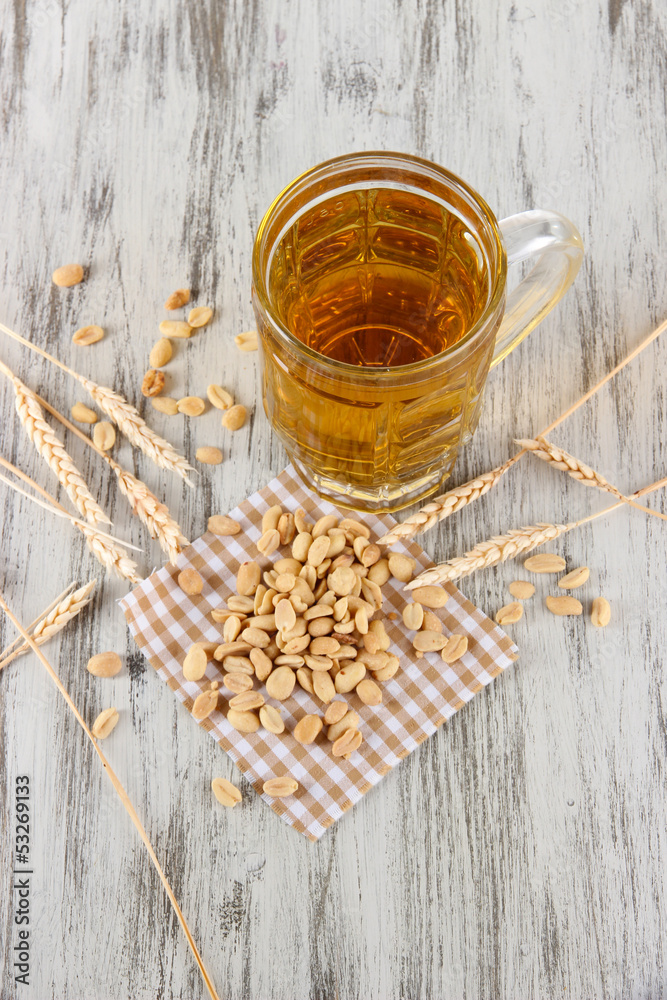 Beer in glass and nuts on napkin on wooden table