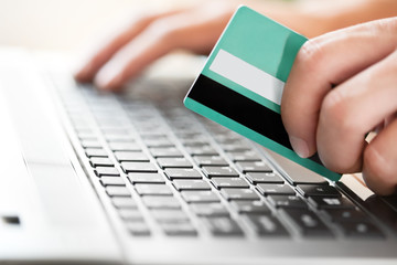 Man holding credit card in hand and entering security code using