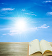 open book on wood and sunshine blue sky