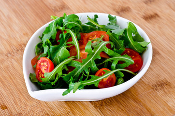 bowl of fresh green, natural arugula and cherry tomatoes