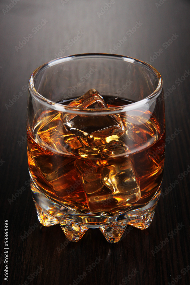 Brandy glass with ice on wooden background