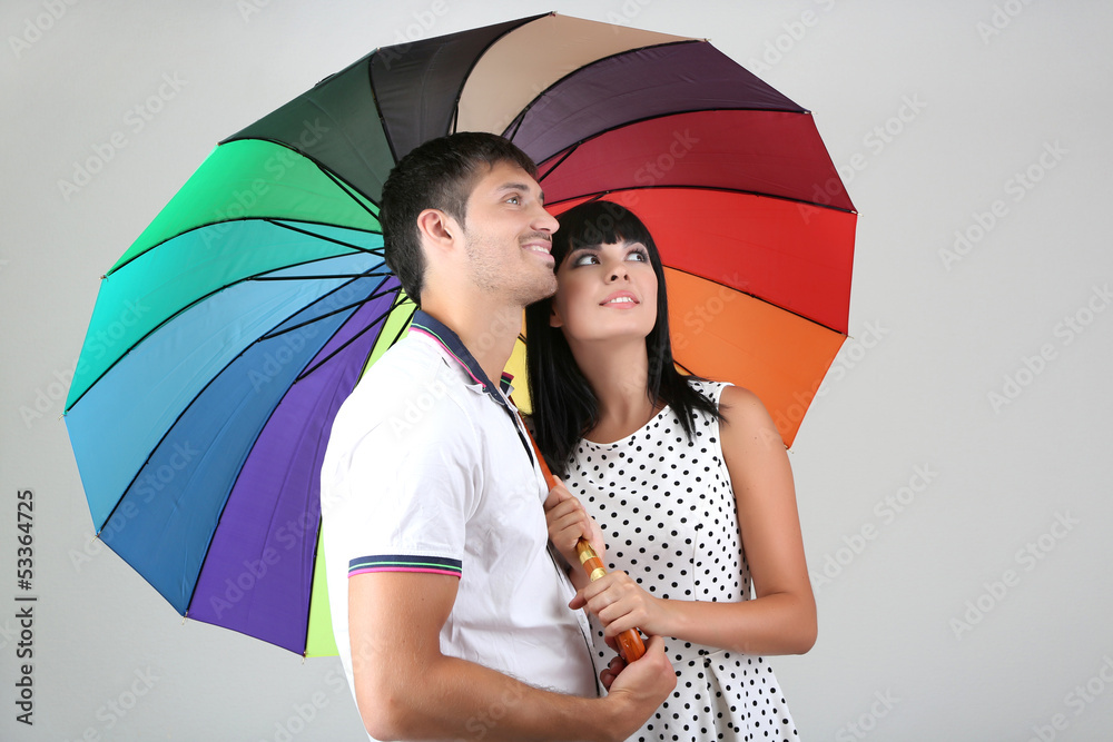 Beautiful loving couple with umbrella on grey background