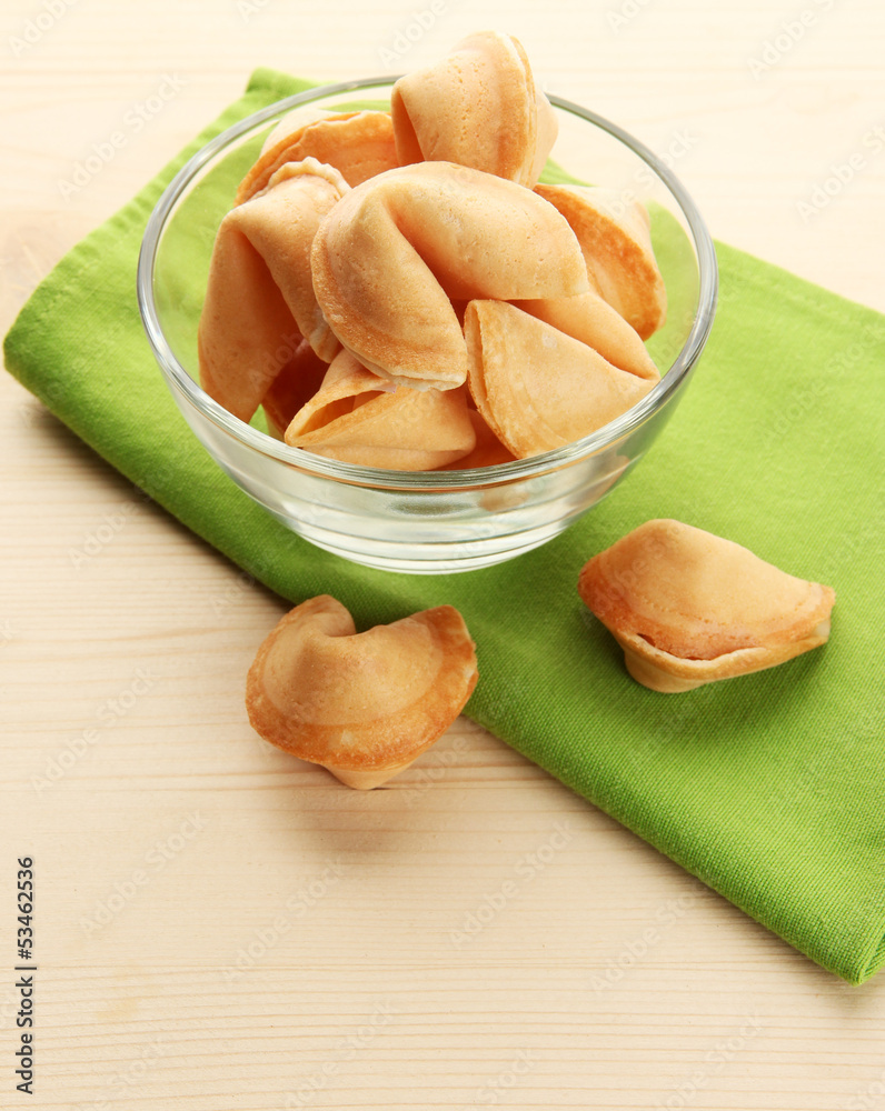 Fortune cookies in bowl, on wooden table