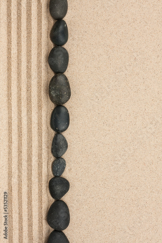 Fototapeta na wymiar Stripe of black stones lying on the sand