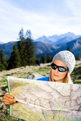 Wall Mural - Woman hiker reading map in mountains