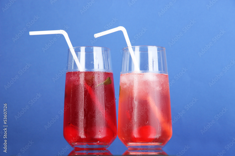 Two cherry cocktails with ice on blue background