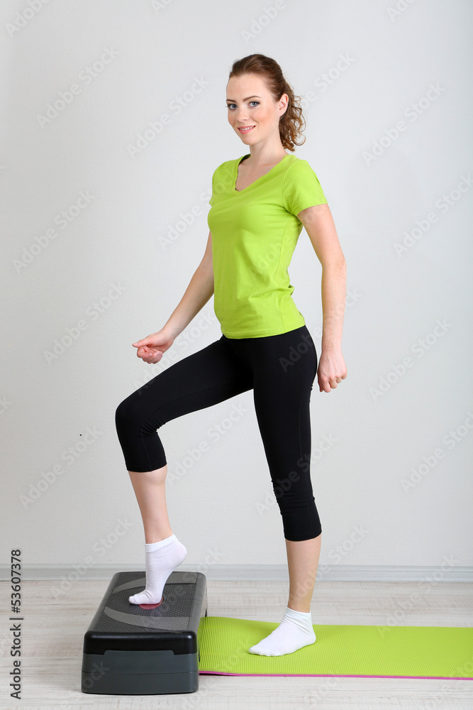 Beautiful young woman exercises on stepper