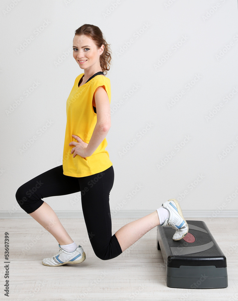 Beautiful young woman exercises on stepper
