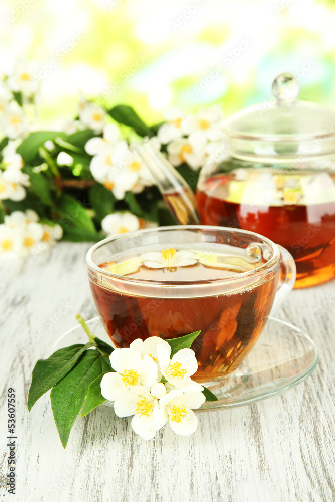 Cup of tea with jasmine, on wooden table, on bright background