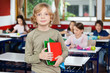 © Tyler Olson - Schoolboy Holding Books While Standing In Classroom