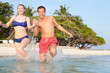 © Monkey Business - Couple Splashing In Sea On Tropical Beach Holiday