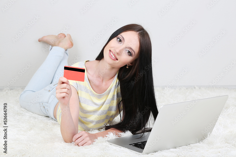 Beautiful young woman lying with laptop in room