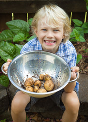 A happy child holding a bowl of organic potoatoes