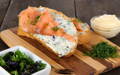 Fish sandwiches on cutting board on wooden table