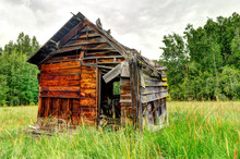 Abandoned Wooden Shed In A Grass Field