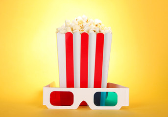 Popcorn and 3D glasses on yellow background