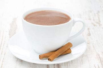 cup of cocoa with cinnamon on a white table, horizontal