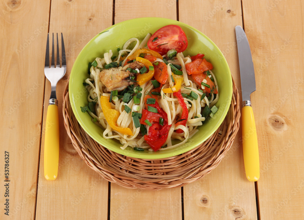 Noodles with vegetables on plates on wooden background