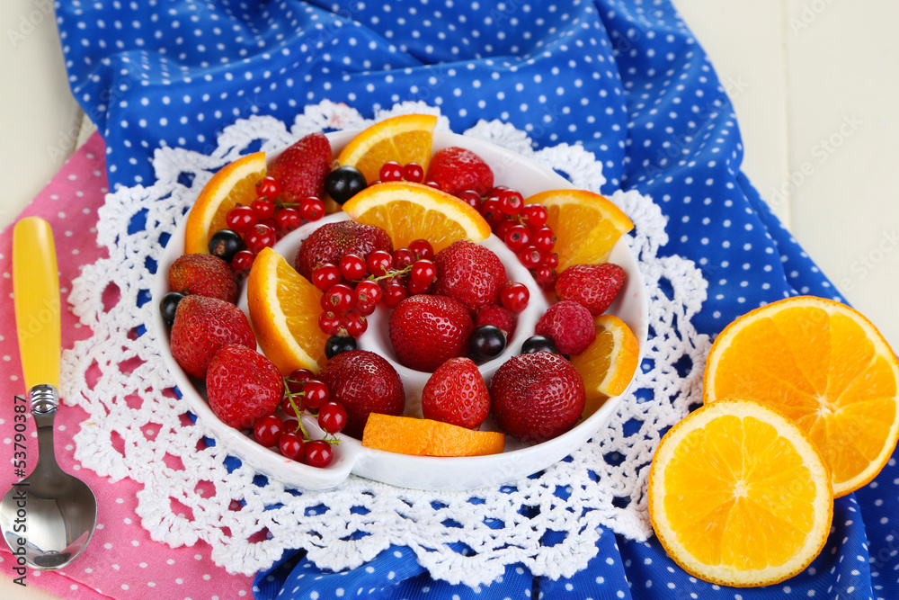 Useful fruit salad in plate on wooden table close-up