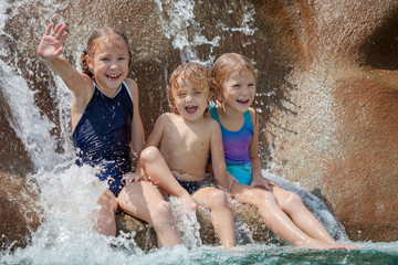 Canvas Print - three happy kids sitting near the pool in the waterpark