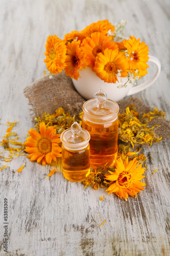 Medicine bottles and calendula flowers on wooden background