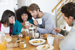 © onoky - Friends sitting at a dining table and looking at a mobile phone