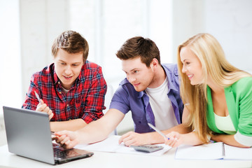 Wall Mural - smiling students looking at laptop at school