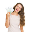 © Alliance - Happy young woman with euros looking up on copy space