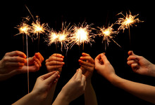 beautiful sparklers in hands on black background.