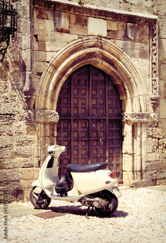 Obraz w ramie White vintage scooter near medieval gate