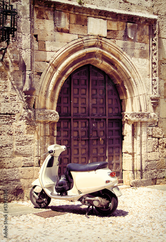 Naklejka na szafę White vintage scooter near medieval gate