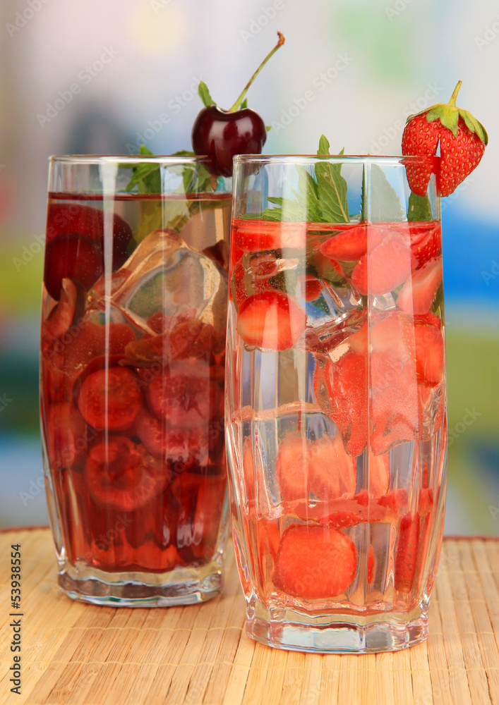 Glasses of fruit drinks with ice cubes on table in cafe