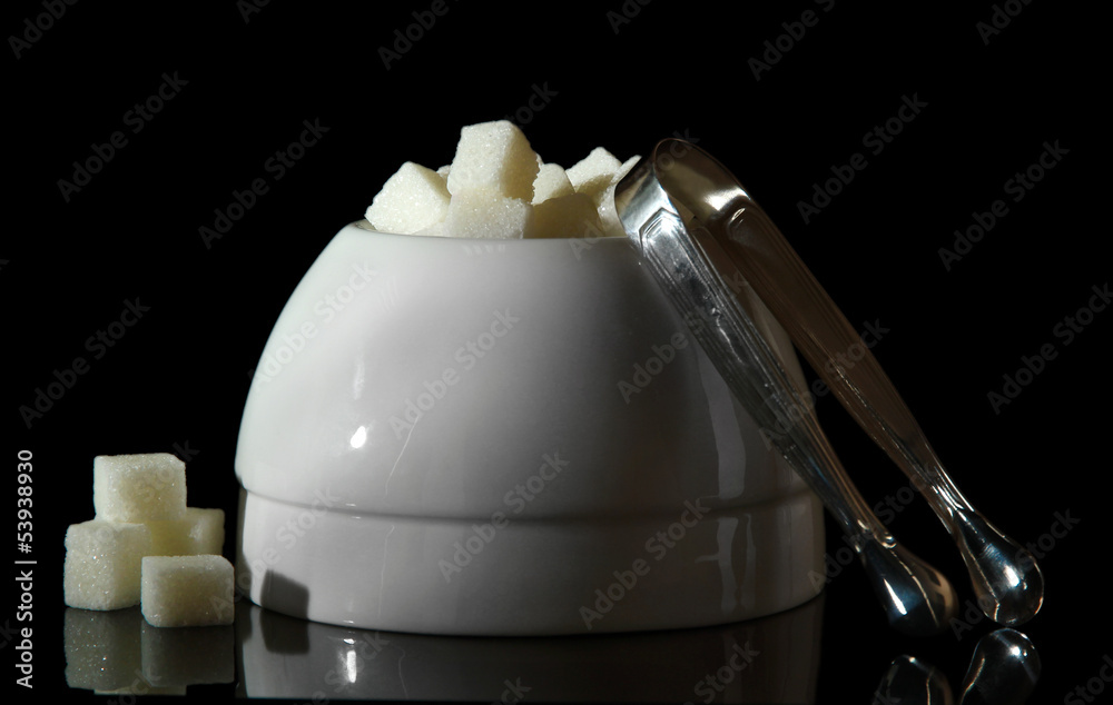 Refined sugar in white sugar bowl on black background