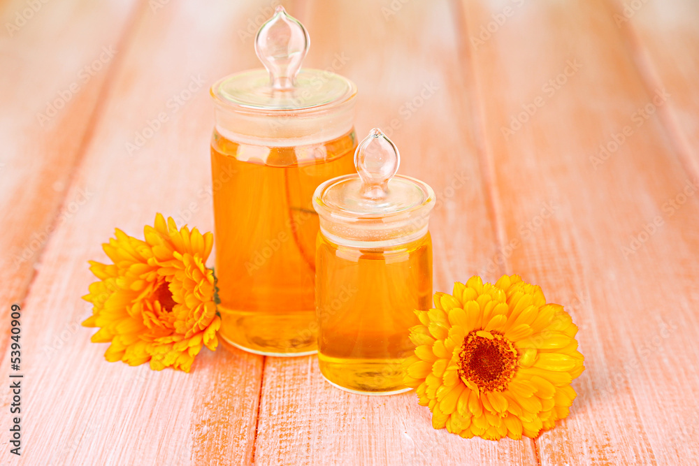 Medicine bottles and calendula flowers on wooden background