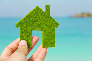 Fototapete - Hand holding green house icon with nature background