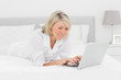 © WavebreakmediaMicro - Smiling woman using her laptop on her bed