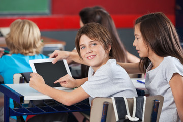 Boy With Girl Using Digital Tablet At Desk