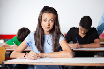 Portrait Of Teenage Schoolgirl Writing At Desk
