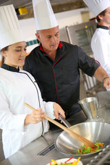 Wall Mural - Chef teaching student how to prepare wok dish