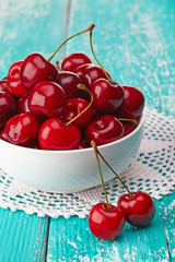 Wall Mural - Bowl of fresh red cherries on blue wooden background