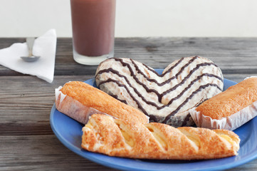 Some pastries in a plate and a chocolate milk glass