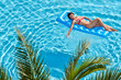 © Pavel Losevsky - Woman in red swimsuit sunbathes on inflatable mattress in pool