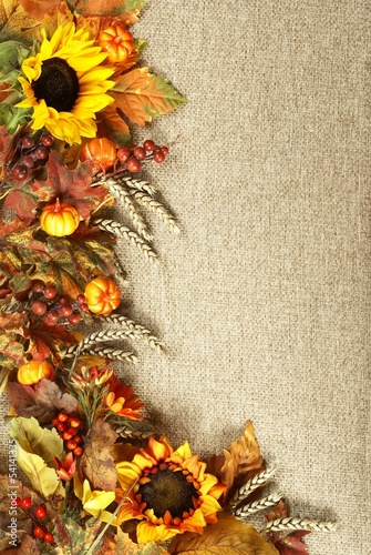 Fototapeta na wymiar Sunflower, autumn leaves and fruits on burlap background