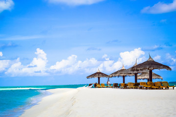 Wall Mural - Beach chairs and grass umbrellas at resort